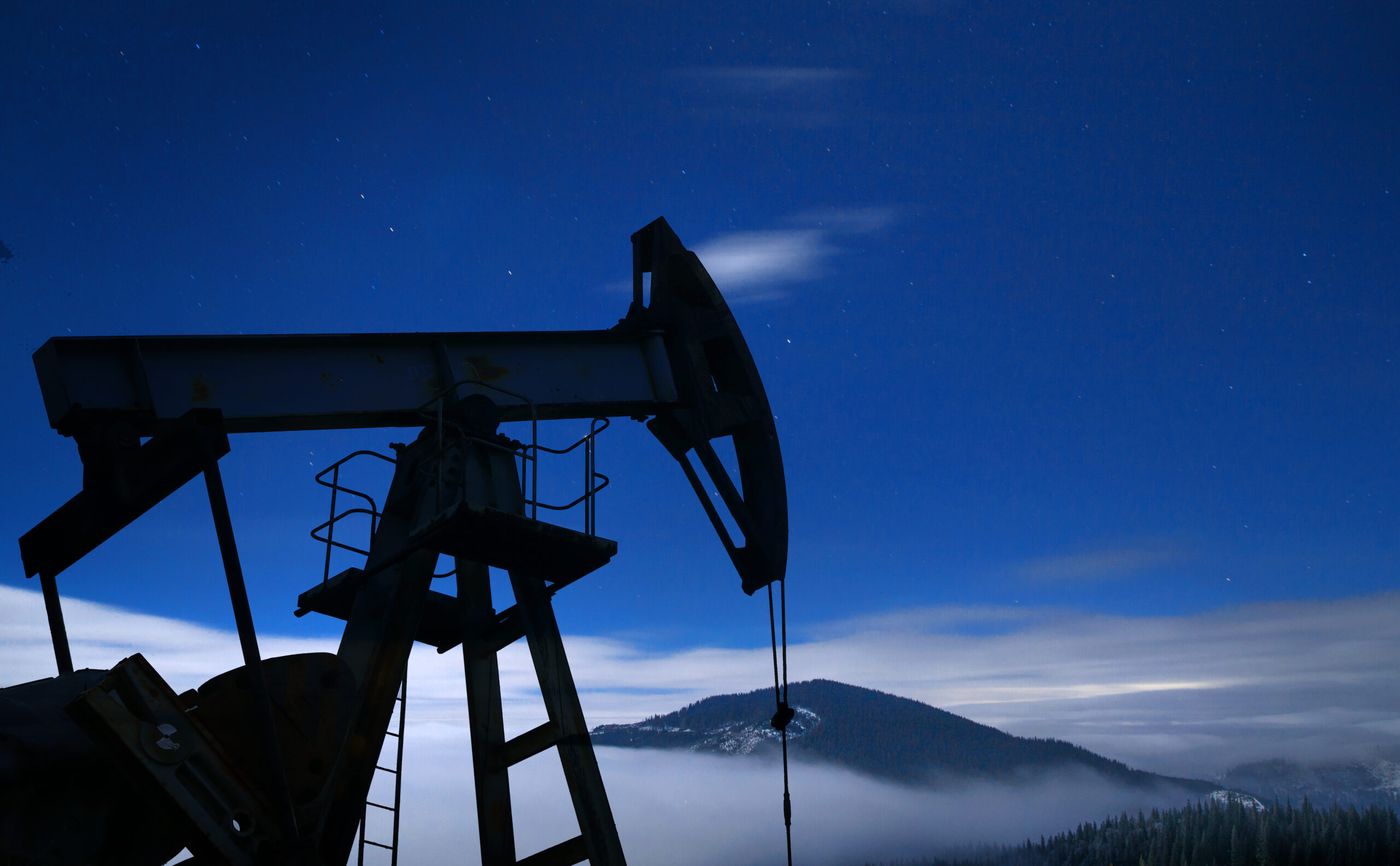 Oil pump silhouette at night. Delta Plus Energy